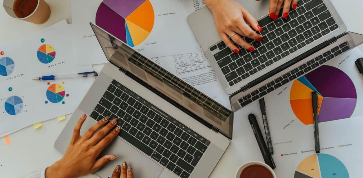 Automatización de procesos administrativos: dos profesionales analizan datos en portátiles con gráficos